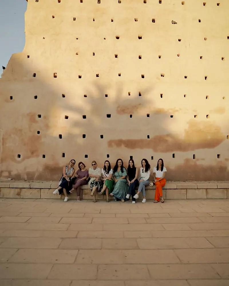 Grupo da LG Viagens sentado num muro ocre, no Marrocos